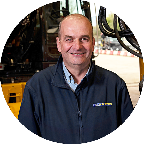 Carl Chippendale, Director King Rail, smiling portrait with rail equipment in background.