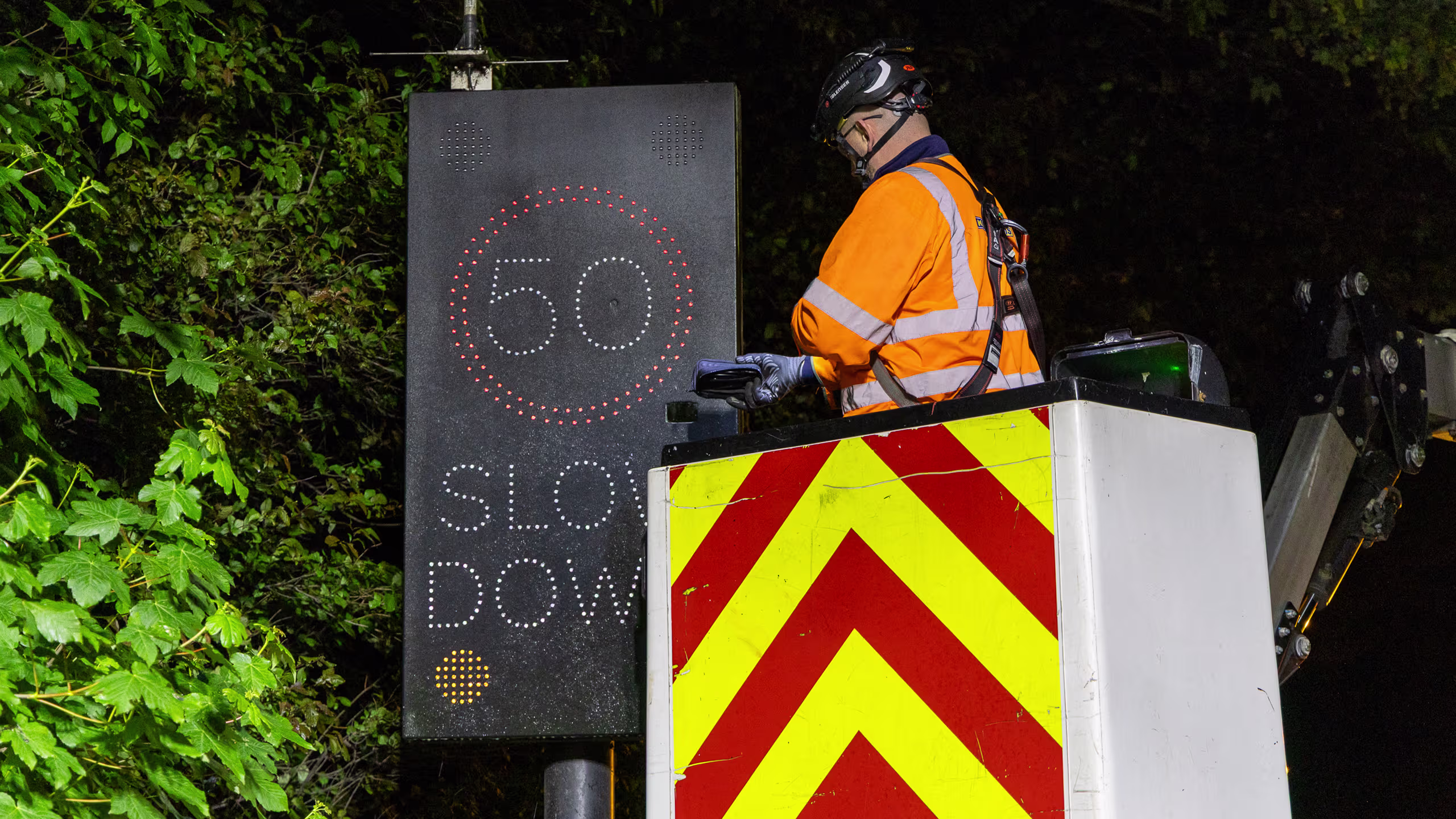 King AVMS technician maintaining highway traffic management system with illuminated speed sign.