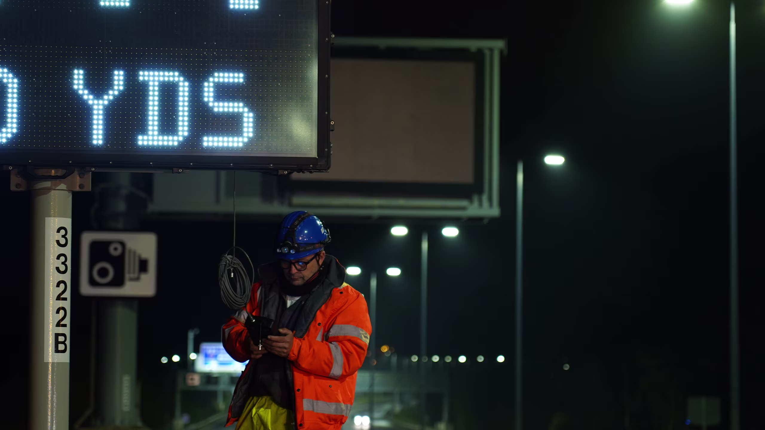 King AVMS variable message sign displaying road safety information at night, with worker and CCTV in background.