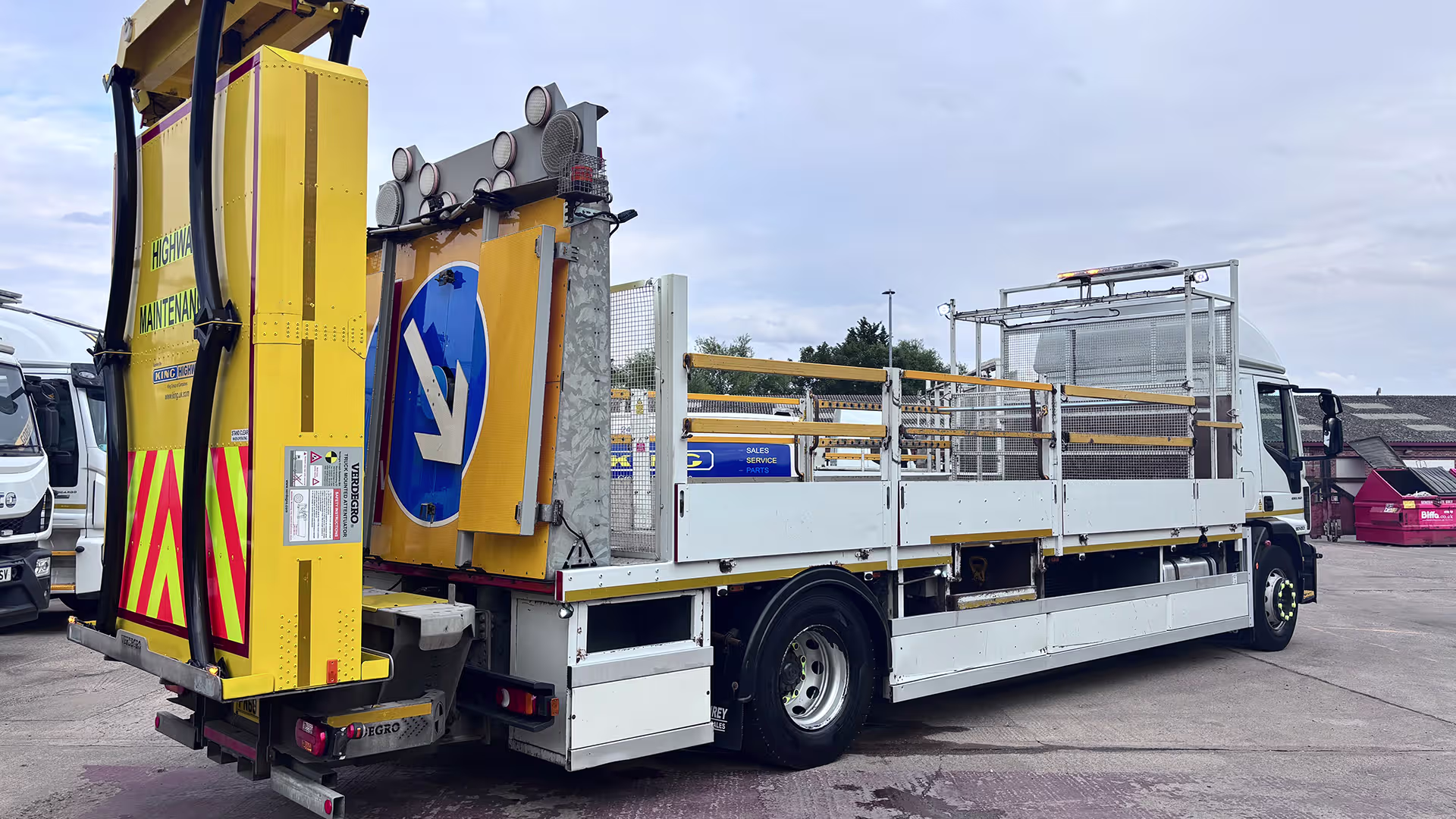 Rear of a large yellow maintenance truck with a hydraulic lift and safety rails, parked on a lot.